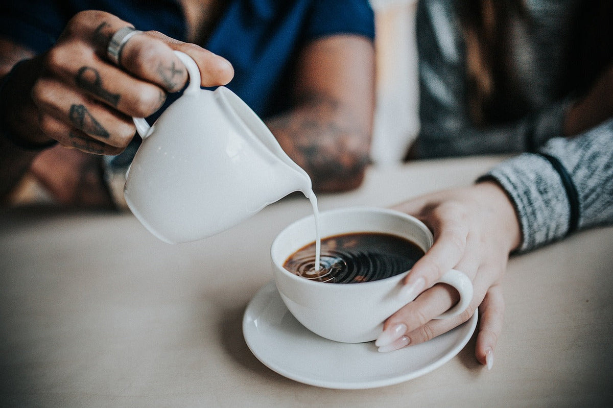 Tee mit Milch: Eine Tradition, die verbindet – Milch wird in eine Tasse Tee gegossen.